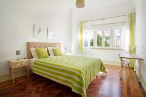 リスボンにあるQuartos do Marquêsのベッドルーム1室(緑と白の毛布付きのベッド1台付)