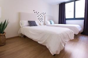 1 dormitorio con 2 camas y ventana en Apartments Olé - Albareda 24, en Sevilla