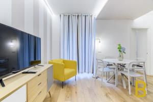 Sala de estar con silla amarilla y mesa en BePlace Apartments in Porta Venezia, en Milán