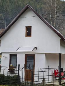 ein weißes Haus mit einem schwarzen Zaun in der Unterkunft Tiny house Floare de colt in Moieciu de Sus