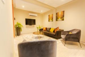 sala de estar con sofá, sillas y TV en Accra Luxury Homes @ Achimota, en Chantan