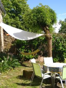 una hamaca en el jardín con mesa y sillas en La longère d'Anaïde en Saint Marcel Campes