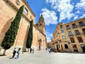 un groupe de personnes marchant dans une cour avec une tour d'horloge dans l'établissement Hideaway Plaza Mayor Salamanca, à Salamanque