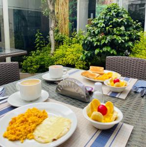 a table with plates of food and cups of coffee at Hotel Marbella Chico in Bogotá