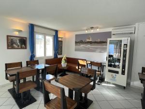 a restaurant dining room with wooden tables and chairs at Hôtel Les Arcades in Saintes-Maries-de-la-Mer