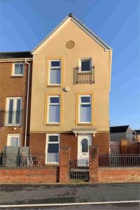 a yellow house with a fence in front of it at Beachfront pet friendly townhouse, Stunning views in Port Talbot