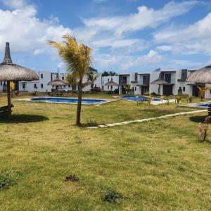 een resort met een palmboom en een zwembad bij North Mauritius New-built 2-bedroom Villa with shared pool in Grand Gaube