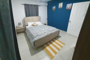 een slaapkamer met een bed en een blauwe muur bij North Mauritius New-built 2-bedroom Villa with shared pool in Grand Gaube