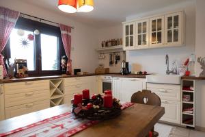 a kitchen with white cabinets and a table with red candles at Knusperhäuschen in Sattendorf