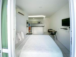 1 dormitorio blanco con 1 cama grande y cocina en H Ponta Negra Beach - Luxo, en Natal