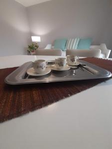 un plateau avec trois tasses et soucoupes sur une table de salon dans l'établissement Departamento MICHE, à Tandil