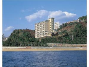 un gran edificio en la cima de una colina junto al agua en Hotel Mikawa Kaiyoukaku - Vacation STAY 90625v en Gamagori