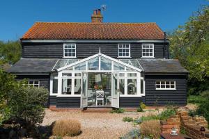 een zwart-wit huis met een serre bij Navigation Cottage on the Historic Sea Lock overlooking the Nature Reserve in Maldon