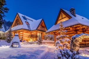 a log cabin in the snow at night at Luxury Chalet Wioska Jagny in Poronin