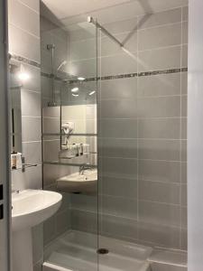 La salle de bains est pourvue d'une douche en verre et d'un lavabo. dans l'établissement Hôtel Les Arcades, à Saintes-Maries-de-la-Mer