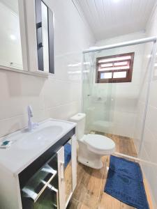 een witte badkamer met een toilet en een wastafel bij Pousada do Primo in Capão da Canoa
