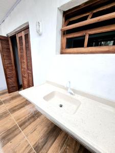 bagno con lavandino bianco e pavimento in legno di Pousada do Primo a Capão da Canoa