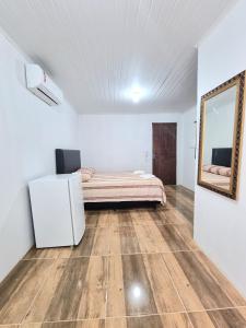 een slaapkamer met een bed en een spiegel aan de muur bij Pousada do Primo in Capão da Canoa