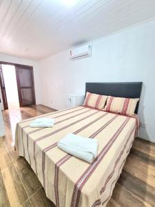 a bedroom with a large bed with two towels on it at Pousada do Primo in Capão da Canoa