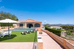 a house with a swimming pool with chairs and an umbrella at Villa Andres - PlusHolidays in Calpe