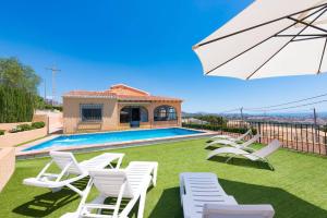 a group of chairs and an umbrella next to a swimming pool at Villa Andres - PlusHolidays in Calpe