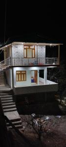 a white house with a porch and stairs at night at Shrikanth Homestay in Joshīmath