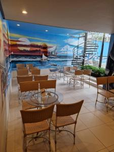 a room with tables and chairs and a mural of a ship at Hotel Encontro do Sol in Fortaleza