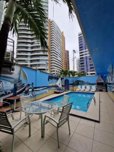 um pátio com uma mesa e cadeiras ao lado de uma piscina em Hotel Encontro do Sol em Fortaleza