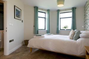 a bedroom with a large white bed with two windows at The Hexagon, wow what a location, views over the Essex marshes and sea in West Mersea