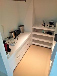 a kitchen with white drawers and shelves with a microwave at Kaap Hoorn Club Bed en Breakfast in Hoorn