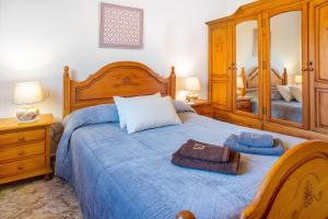 1 dormitorio con 1 cama grande de madera con manta azul en Casa Juana, en Agua de Fontanales