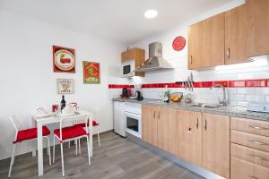 a kitchen with wooden cabinets and a table with red accents at Casa Timanfaya in Playa Blanca