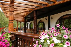 a wooden deck with tables and chairs and flowers at Casa Baciu Colacu in Fundu Moldovei