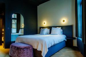 a bedroom with a large bed with a purple stool at Hotel Montanus in Bruges
