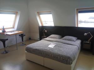 een slaapkamer met een bed, een tafel en 2 ramen bij Kaap Hoorn Club Bed en Breakfast in Hoorn