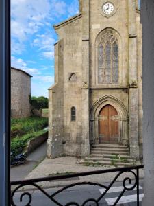an old church with a wooden door and a clock at Le Logis du Donjon 1 in Les Herbiers
