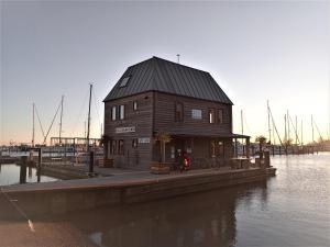 a wooden building on a dock next to the water at Kaap Hoorn Club Bed en Breakfast in Hoorn