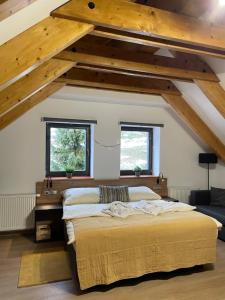 a bedroom with a large bed and two windows at Apartmány Výsluní in Špindlerův Mlýn