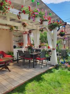 un patio con una mesa y sillas bajo una pérgola con flores en Casa Doina, en Râșnov
