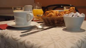 - une table avec deux tasses et un panier de pâtisseries dans l'établissement Hotel Camelia, à Boulogne-Billancourt