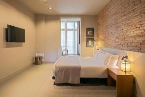 a bedroom with a large bed and a brick wall at Uma Suites Pau Claris in Barcelona