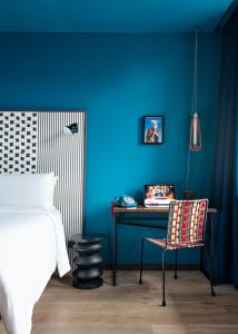 a bedroom with a blue wall with a desk and a chair at BOMA easy living hotel in Strasbourg