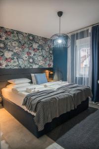 - une chambre avec un grand lit et un mur fleuri dans l'établissement Apartmani Darijana, à Ljubovija