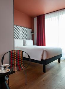 - une chambre avec un grand lit et une chaise dans l'établissement BOMA easy living hotel, à Strasbourg