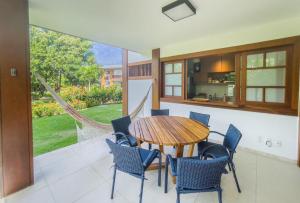 eine Küche und ein Esszimmer mit einem Holztisch und Stühlen in der Unterkunft Villa da Enseada, Praia do Forte in Mata de Sao Joao
