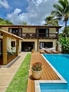 ein Haus mit einer Holzterrasse und einem Pool in der Unterkunft Suites Taipe in Trancoso