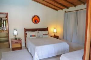 a bedroom with a large bed and two lamps at Suites Taipe in Trancoso