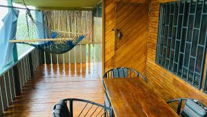 Pacific Edge Eco Lodge في دومينيكال: شرفة مع أرجوحة وطاولة وكراسي خشبية