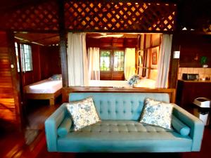a blue couch in a room with two beds at Pacific Edge Eco Lodge in Dominical