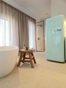 a bathroom with a tub and a table and a refrigerator at Ivy's Natural Resort in Arnados